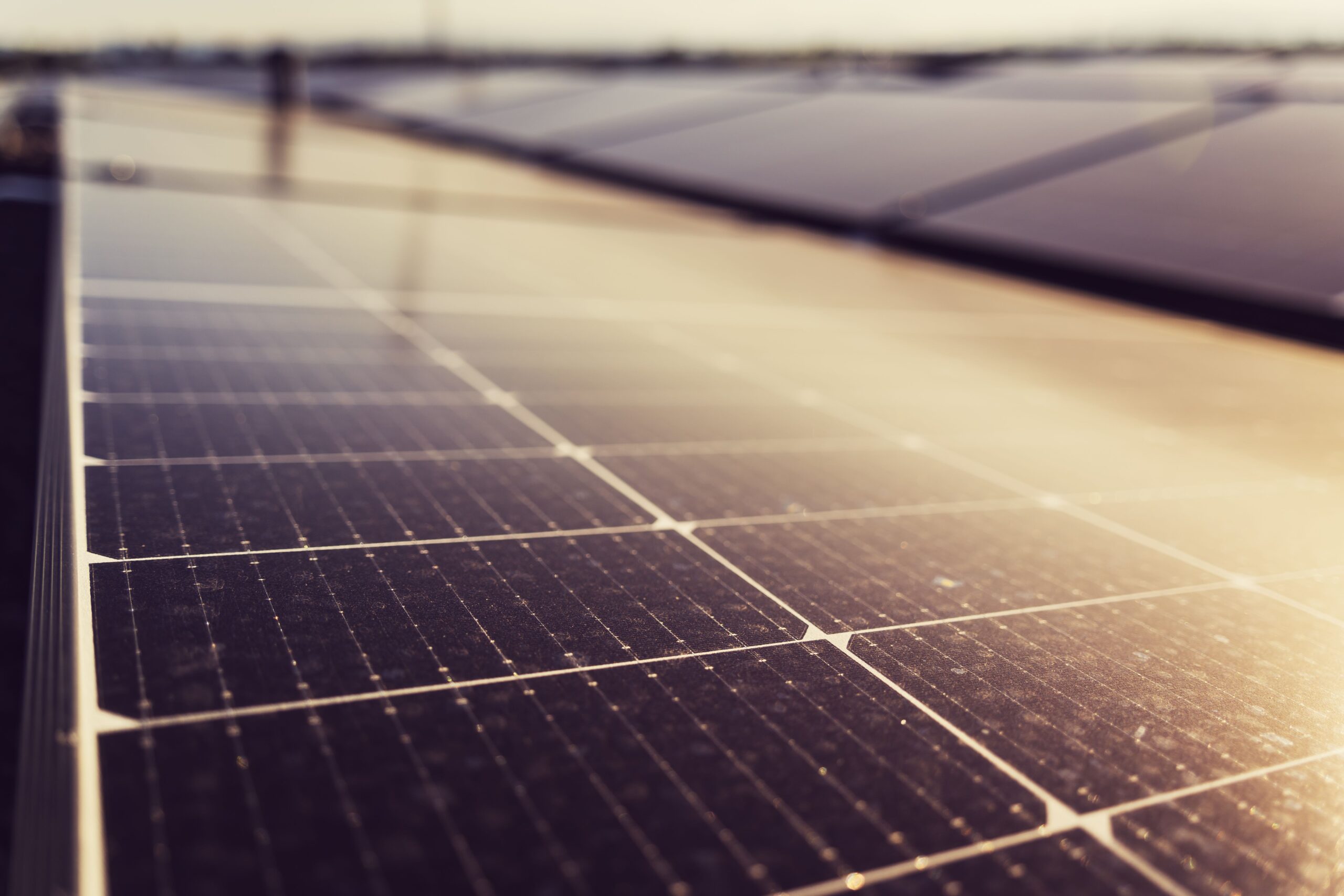 Solar panels on a rooftop capturing sunlight with a hazy sky in the background (blurred).
